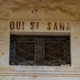 Sulla porta di ingresso, al di sopra di una grata in ferro rettangolare, leggiamo la scritta Qui si sana, un motto presente in tante ville e masserie dell�epoca